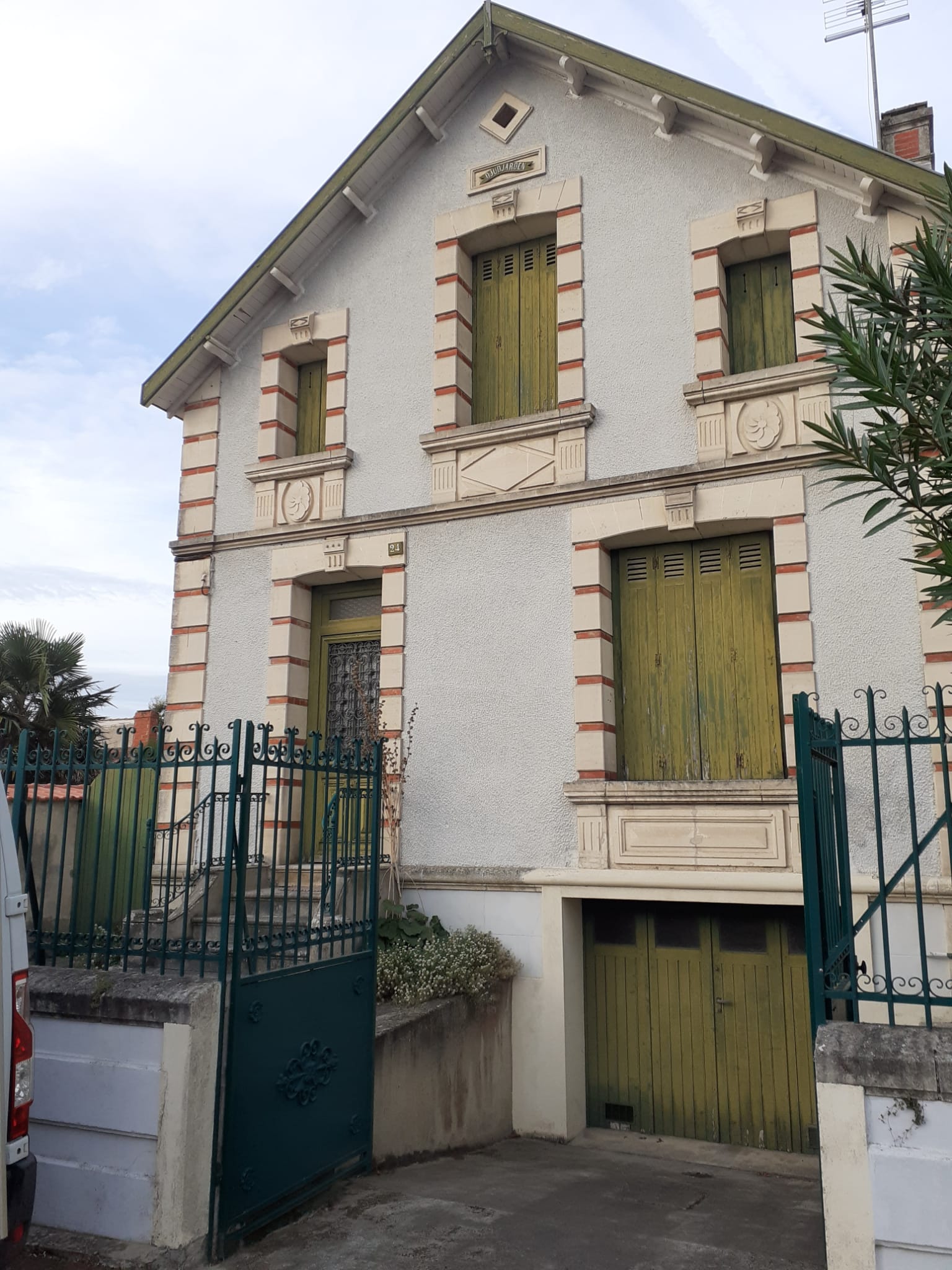 Façade avant travaux avec d'anciens volets battants en bois vert délavé